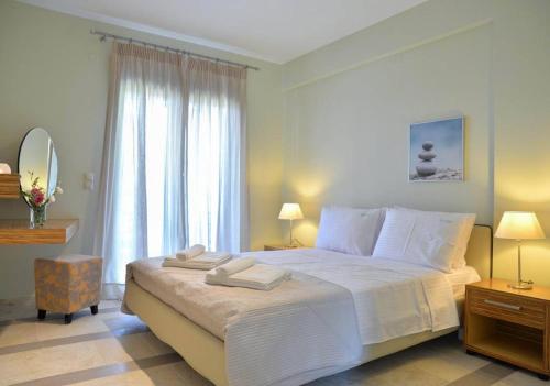 a bedroom with a white bed with two towels on it at Drimonari Villas in Agios Nikitas
