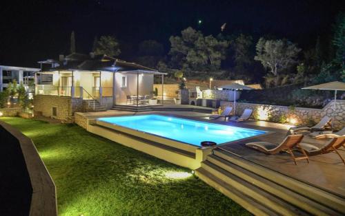 a swimming pool in the yard of a house at night at Drimonari Villas in Agios Nikitas