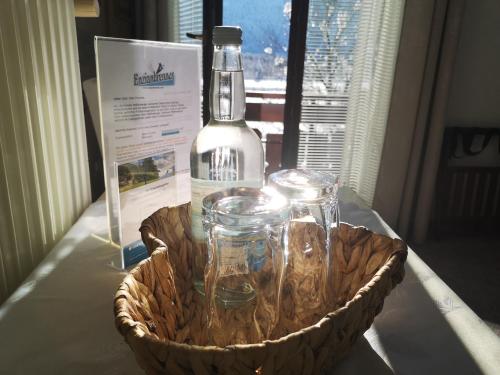 a bottle of wine and glasses in a basket on a table at Enzianbrenner in Jenig