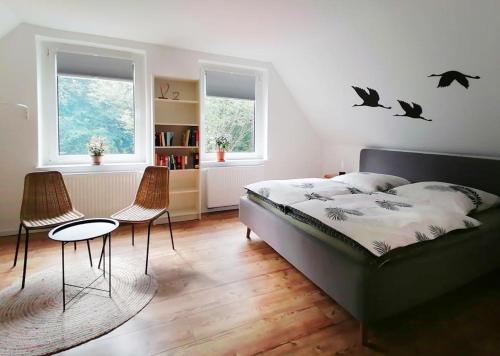 een slaapkamer met een bed en twee stoelen en vleermuizen aan de muur bij Ferienhaus BB2 in Bad Brambach