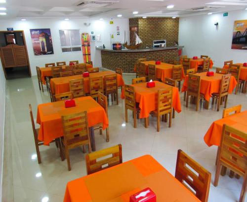 an empty restaurant with orange tables and chairs at Hotel NelyMar in Santa Marta