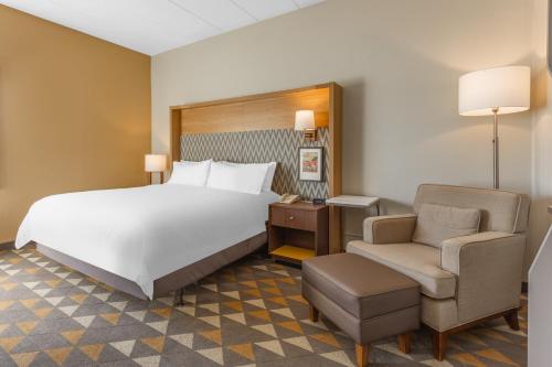 a bedroom with a large white bed and a chair at Holiday Inn Rockford by IHG in Rockford