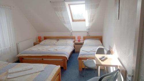 a room with three beds and a table and a window at Penzion Pristav in Lipno nad Vltavou