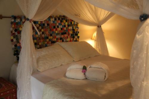a bed with two pillows on top of it at Sítio Pássaro Ímpar - Para pousar e repousar in Curuçá