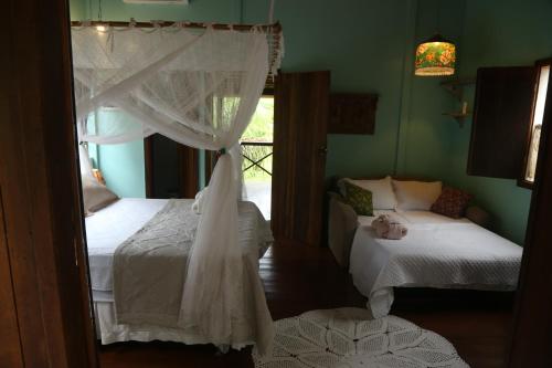 a bedroom with two beds and a window at Sítio Pássaro Ímpar - Para pousar e repousar in Curuçá