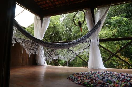 a hammock in a room with a rug on the floor at Sítio Pássaro Ímpar - Para pousar e repousar in Curuçá