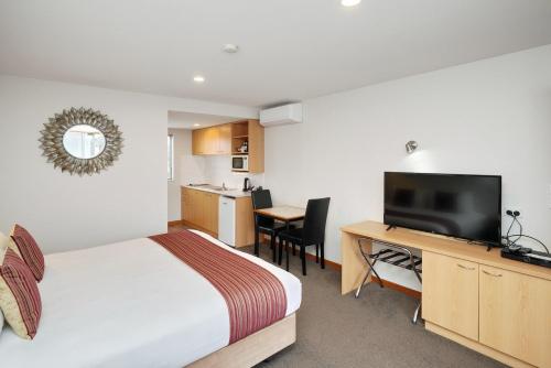 a hotel room with a bed and a desk with a television at 306 Motel Apartments in Christchurch