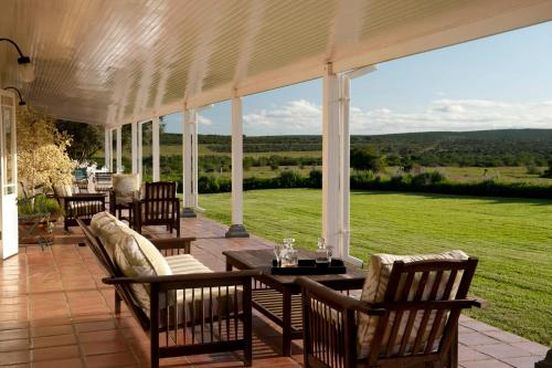a patio with a table and chairs and a large window at River Bend Lodge in Addo