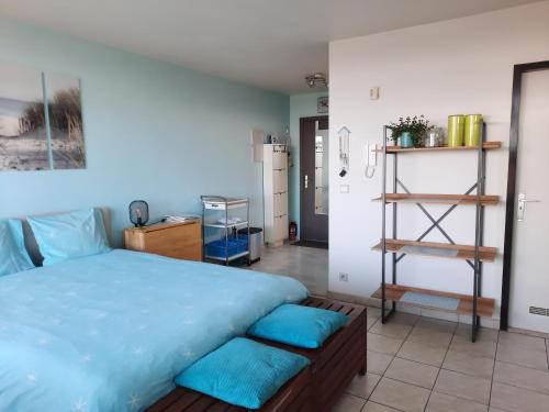 een slaapkamer met een groot bed met blauwe lakens bij Studio with sea view and panoramic view in Bredene in Bredene