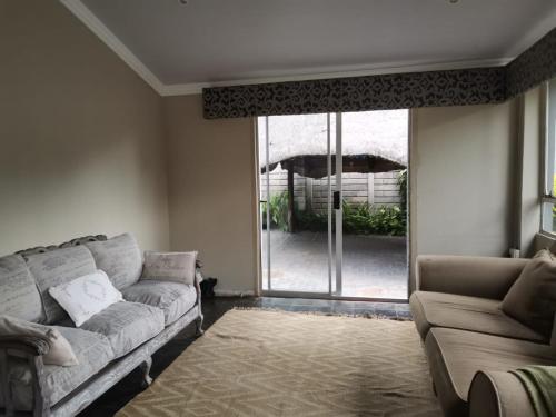 a living room with a couch and a sliding glass door at Bono Luxury Guesthouse in Rustenburg