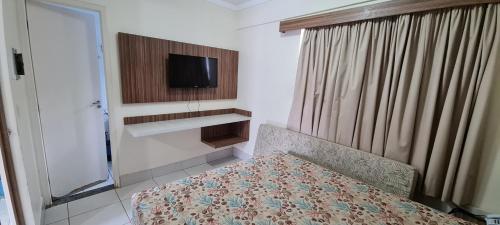 a bedroom with a bed and a tv on the wall at Lacqua diRoma 1 - Apartamentos JN in Caldas Novas
