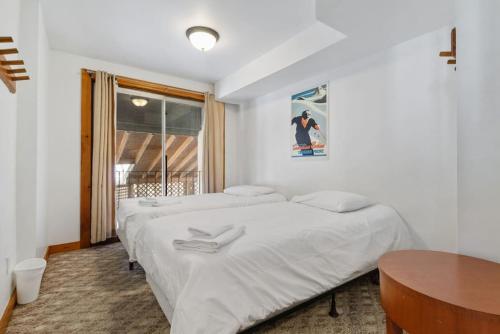 two beds in a room with a table and a window at 12 Beds Sleep 16 Chalet with HotTub, 2min to Blue in Blue Mountains