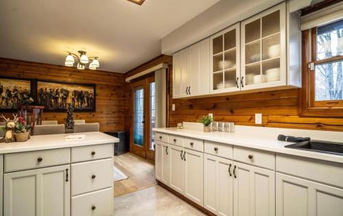 cocina con armarios blancos y paredes de madera en Minnies Mountain Lake House, en La Follette