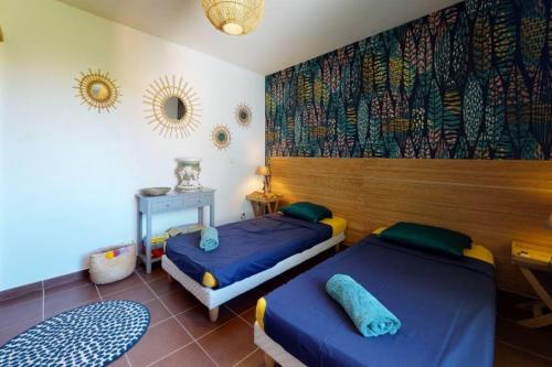 a bedroom with two beds and a wall with a mural at ilococo in Sainte-Anne