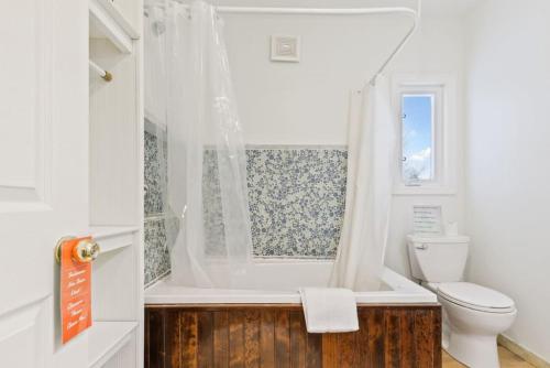 a white bathroom with a tub and a toilet at Paradise Manor w Hot tub Sauna & Putting Green in Blue Mountains