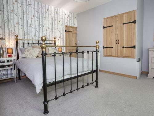 a bedroom with a bed and a wooden cabinet at The Yorkshire Hosts - Fall in Green Cottage in Haworth