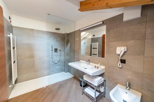 La salle de bains est pourvue d'un lavabo et d'une douche. dans l'établissement Hotel Garnì Paradisi - Wellness & Spa, à Mezzano