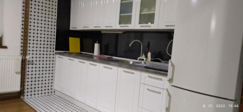 a white kitchen with a sink and a refrigerator at Apartman House Jasmina in Bihać