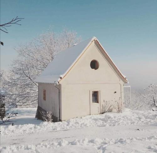 Mała, biała stodoła ze śniegiem na ziemi w obiekcie Weinstöckl in der Südsteiermark w mieście Leutschach