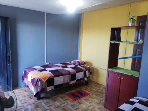 a small room with a bed and a shelf at Hospedaje Arvakeni in San Cristobal
