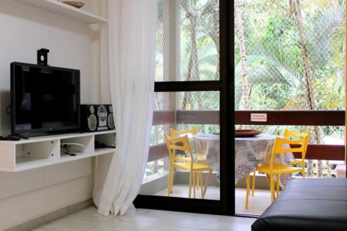 a living room with a tv and a table and chairs at Apto Riviera de São Lourenço com Piscinas Aquecidas,Quadra,Sacada Gourmet in Bertioga