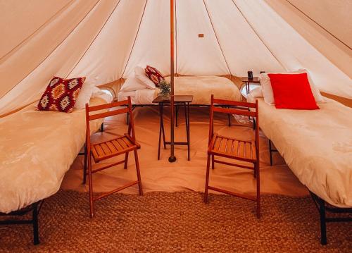 two beds in a tent with two chairs and a table at Wander Camp Yellowstone in Island Park