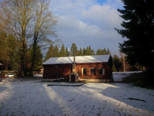 a small wooden house with snow on the ground at Lesní chaty "Hogo Fogo" in Kytlice