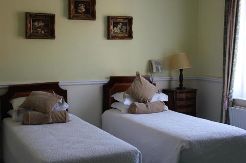a bedroom with two beds with white sheets at Kilcooly's Country House Hotel in Ballybunion