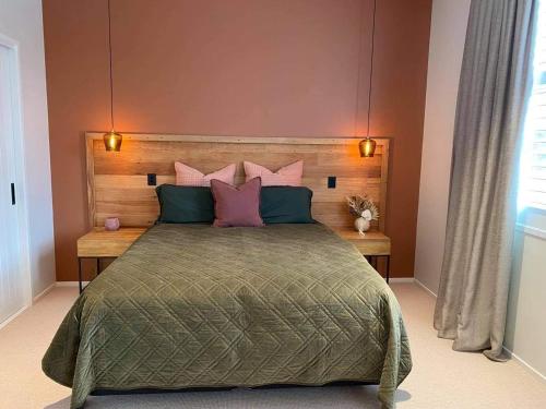 a bedroom with a large bed with pink and green pillows at Rata Boutique Apartments in Ohakune