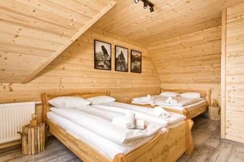 Duas camas num quarto com paredes de madeira em GliczarowSKI em Gliczarów Górny