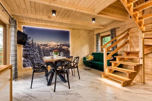 a dining room with a table and a green couch at Domki GliczarowSKI z Jacuzzi & Sauna in Zakopane