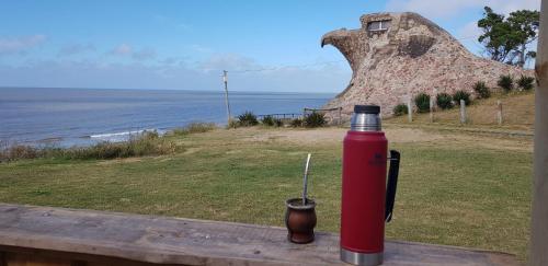 a red fire hydrant sitting on a table near the ocean at La Quimera del Águila in Atlántida