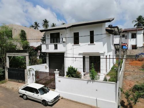 a white house with a car parked in front of it at Weeraman's Vila in Kadawata