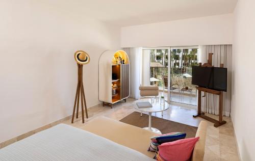 a bedroom with a bed and a living room with a tv at ME Cabo by Meliá in Cabo San Lucas