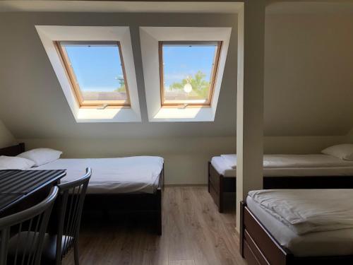 ムジェジノにあるWilla3Dのベッド2台、テーブル、窓2つが備わる客室です。