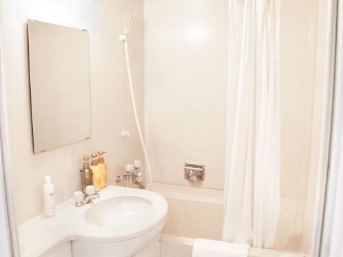 Baño blanco con lavabo y espejo en Hotel Abest Shin-Anjo-Ekimae, en Anjomachi