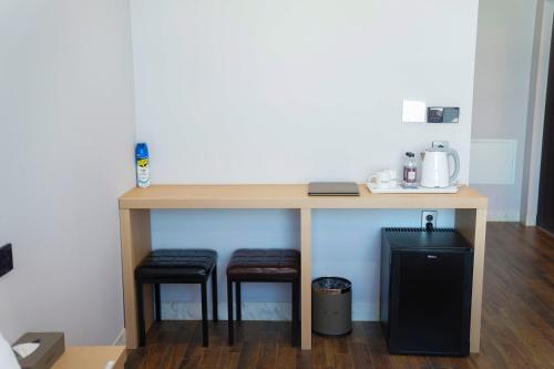 a table with two stools under it with a coffee maker at Aroomi Hotel Hyupjae in Jeju