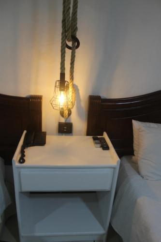 a nightstand with a light next to a bed at Berlor Airport Inn in Alajuela City