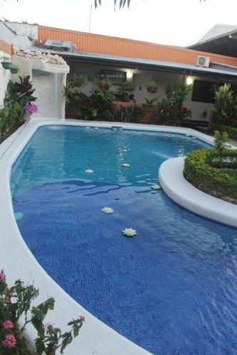 a large pool with blue water in a yard at Berlor Airport Inn in Alajuela City