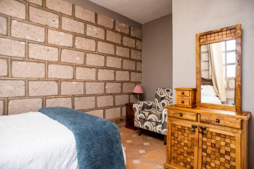a bedroom with a brick wall and a bed and a mirror at Rancho los olivos Habitaciones Campestres in San Miguel de Allende
