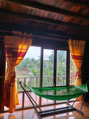 a green hammock in front of a window at FOREST BREATH ECO-LODGE in Tân Phú