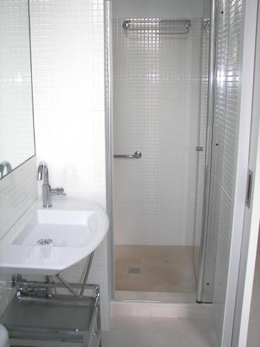a white bathroom with a shower and a sink at Villa Cel in Cala en Blanes