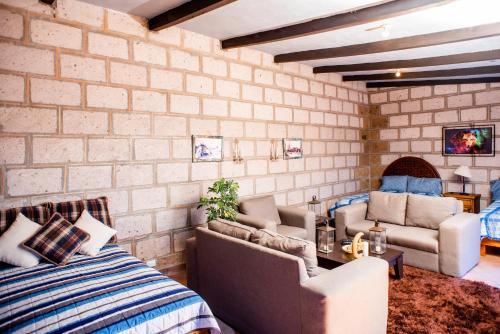 a brick walled room with a bed and chairs at Rancho los olivos Habitaciones Campestres in San Miguel de Allende