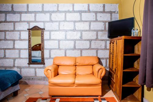 a living room with a brown leather chair and a tv at Rancho los olivos Habitaciones Campestres in San Miguel de Allende