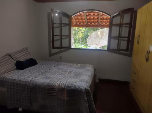 a bedroom with a bed and two windows at Casa Pereira Visconde de Mauá in Visconde De Maua