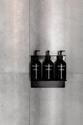 a black shelf with four bottles on a wall at Caroline Serviced Apartments Richmond in Melbourne