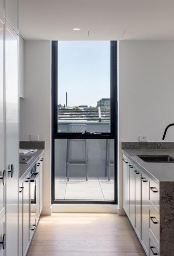 a kitchen with white cabinets and a large window at Caroline Serviced Apartments Richmond in Melbourne