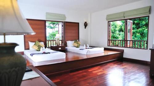 Teak Garden Resort, Chiang Rai في شيانج راي: غرفة كبيرة بسريرين ونوافذ
