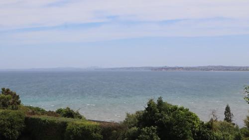 a view of the ocean from a hill at Luxury Holiday home with cliff top sea and city views in Whangaparaoa