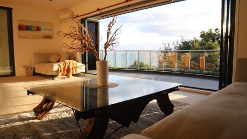 a living room with a table and a large window at Luxury Holiday home with cliff top sea and city views in Whangaparaoa